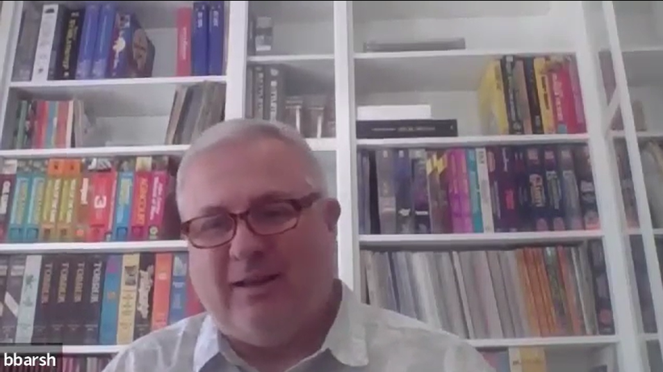 Screenshot of Bill Barsh in front of his bookshelf of games. 